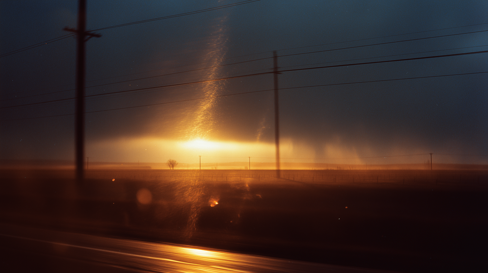 Sunset through power lines over open plains