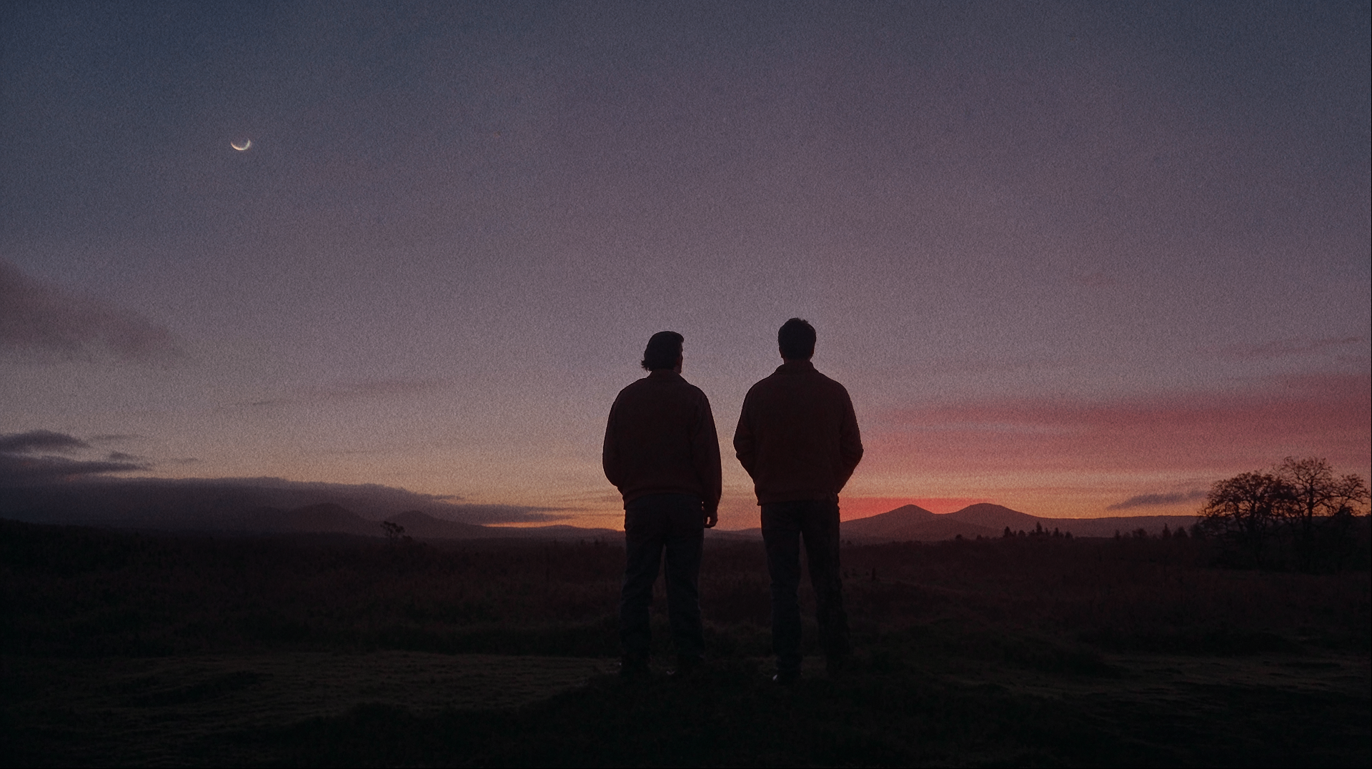 Two friends silhouetted against a sunset sky